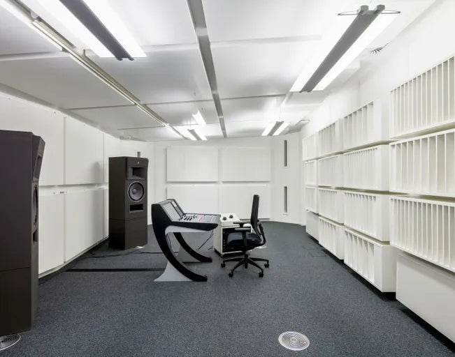 Wide interior view of the precision-engineered critical listening control room at the Max Planck Institute for Empirical Aesthetics in Frankfurt, Germany, highlighting custom floor-standing STRAUSS ELEKTROAKUSTIK main monitors integrated into a minimalist white acoustic wall panel system alongside a specialized production console and central listening desk setup.