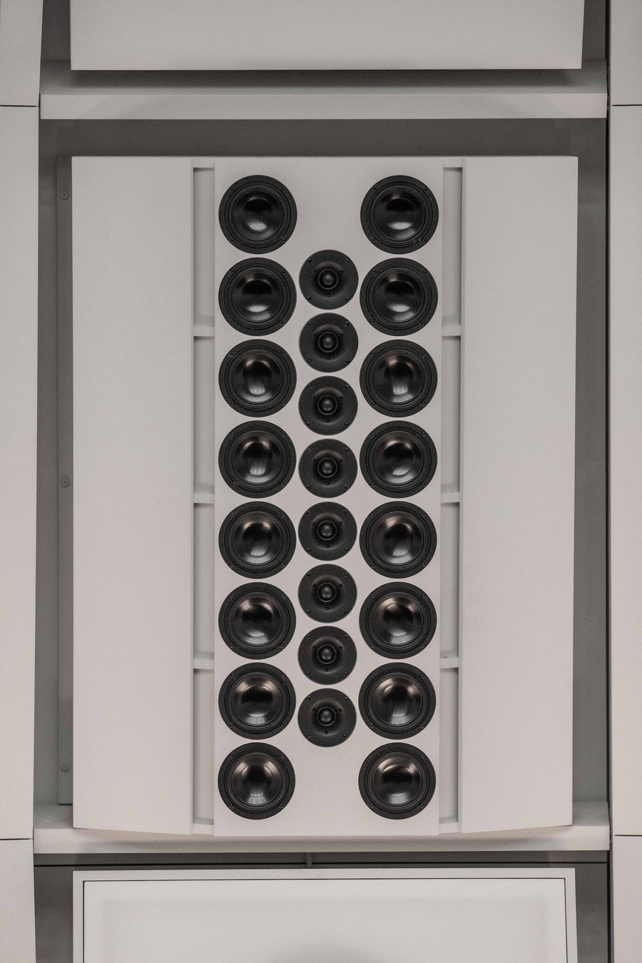 Vertical close-up view inside the acoustic environment of THE LAB at SE MUSICLAB in Bern, Switzerland, showcasing a custom-engineered multi-driver vertical line source loudspeaker array designed by Jürgen Strauss, seamlessly integrated into a decoupled white modular panel system.