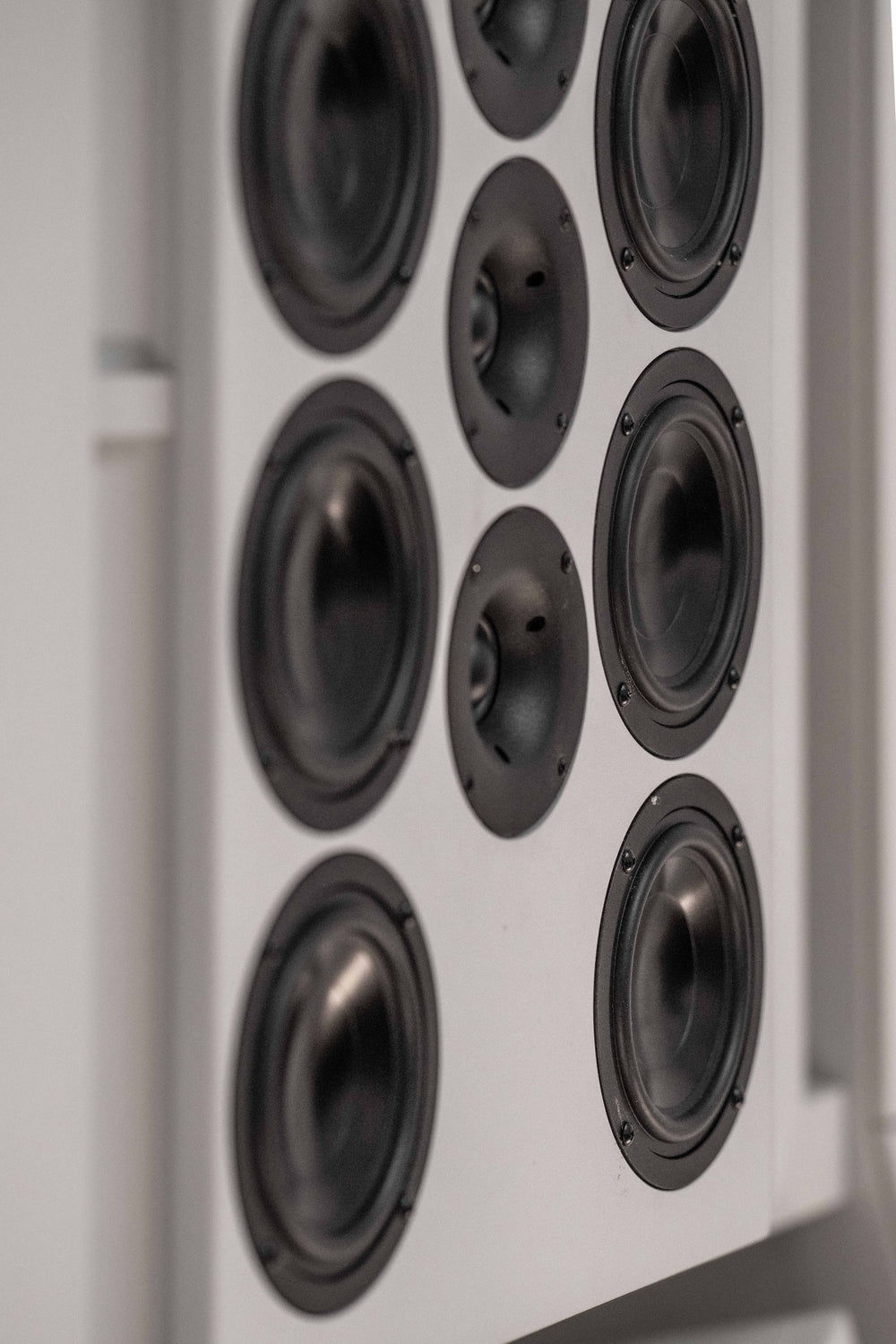 Vertical close-up view inside the precision acoustic environment of THE LAB at SE MUSICLAB in Bern, Switzerland, highlighting a custom-engineered multi-driver vertical line source loudspeaker array designed by Jürgen Strauss, seamlessly integrated into a decoupled white modular panel system.