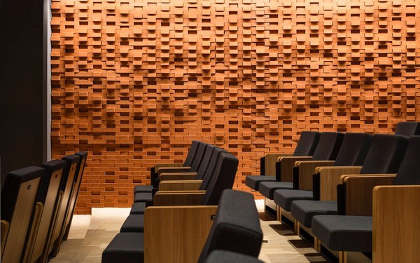 Interior view of the ArtLab lecture and performance hall at the Max Planck Institute for Empirical Aesthetics in Frankfurt, Germany, showcasing rows of modern dark theater seating set against a striking, custom-engineered diffusion wall made of three-dimensional textured wood blocks.