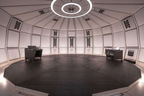 Interior architectural view of the precision-engineered acoustic environment of THE LAB at SE MUSICLAB in Bern, Switzerland, highlighting the decoupled modular wall panels, dark wood floor, and a distinctive multi-ring circular ceiling lighting fixture.