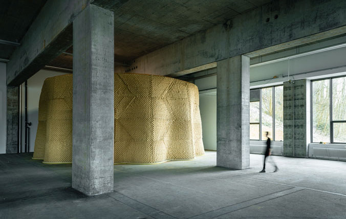 Wide interior view inside THE LAB at SE MUSICLAB in Bern, Switzerland, showing the completed, massive custom acoustic clay wall structure designed by Jürgen Strauss, integrated within a raw concrete architectural space with large minimalist windows.