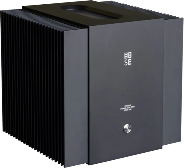 Front three-quarter perspective view of the STRAUSS ELEKTROAKUSTIK SE PA-100 Stereo Power Amplifier on a checkered background, showcasing the minimalist dark grey faceplate with the white vertical SE block logo, massive wrap-around vertical cooling fins, and precision mechanical chassis engineering.