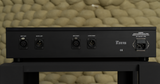 Rear perspective view of the STRAUSS ELEKTROAKUSTIK SE REQ-1S Reference Monitoring and Room Equalizer resting on a studio stand, highlighting the balanced XLR inputs and outputs for independent dual-mono calibration, integrated fuse block power interface, and clean mechanical chassis engineering against a textured background.